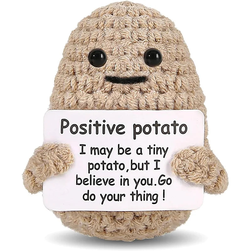 Close-up of a khaki crochet potato doll holding a card that reads: I may be a tiny potato, but I believe in you. Go do your thing! (card design may vary)